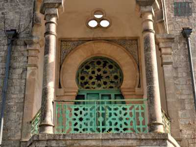 ...� caratterizzato da una balconata con piccolo portico su cui spicca il grande portone in legno verde, sormontato da una griglia traforata